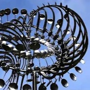 a portion of a kinetic sculpture, shining silver against a blue sky