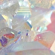 closeup picture of a white crystal with many different colors reflected in its roughly cut faces