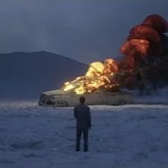 photo of a person standing in the snow, in front of a burning car. plumes of smoke and flame drift into the sky