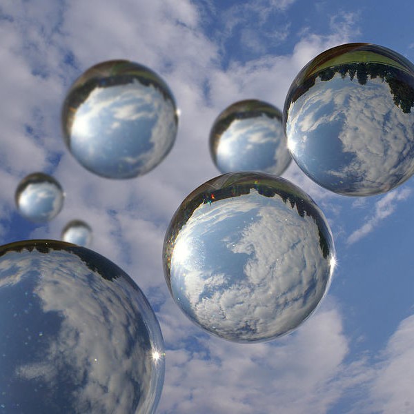 a photo of round glass bubbles floating up into a blue sky